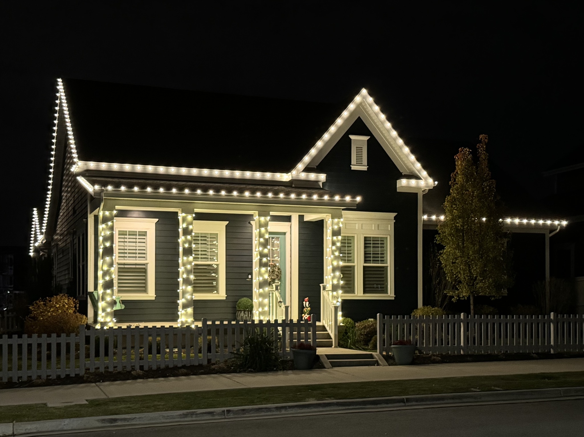 Dark home with warm white roofline lights and illuminated porch columns