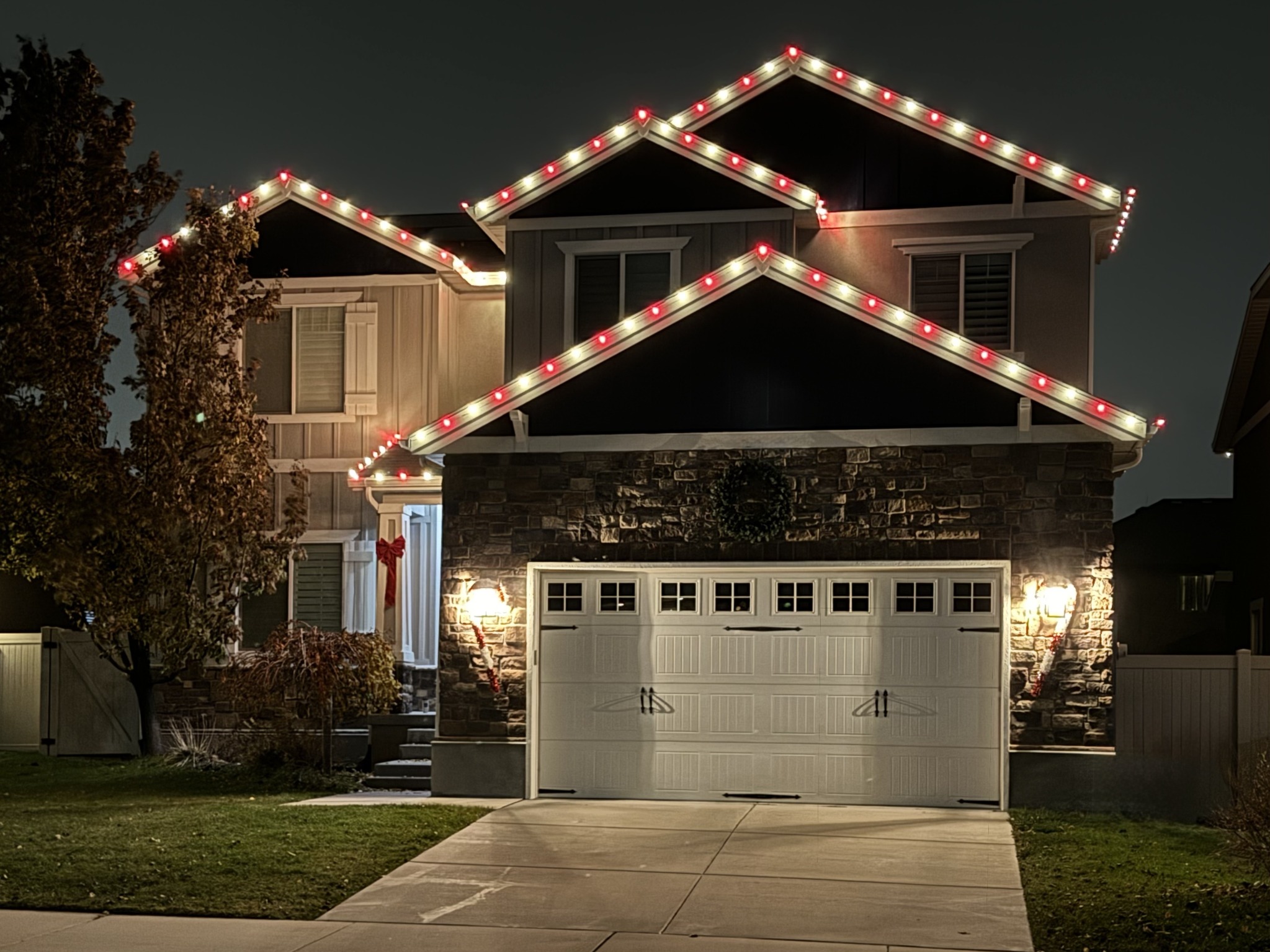 Two-story home with alternating red and warm white roofline lights