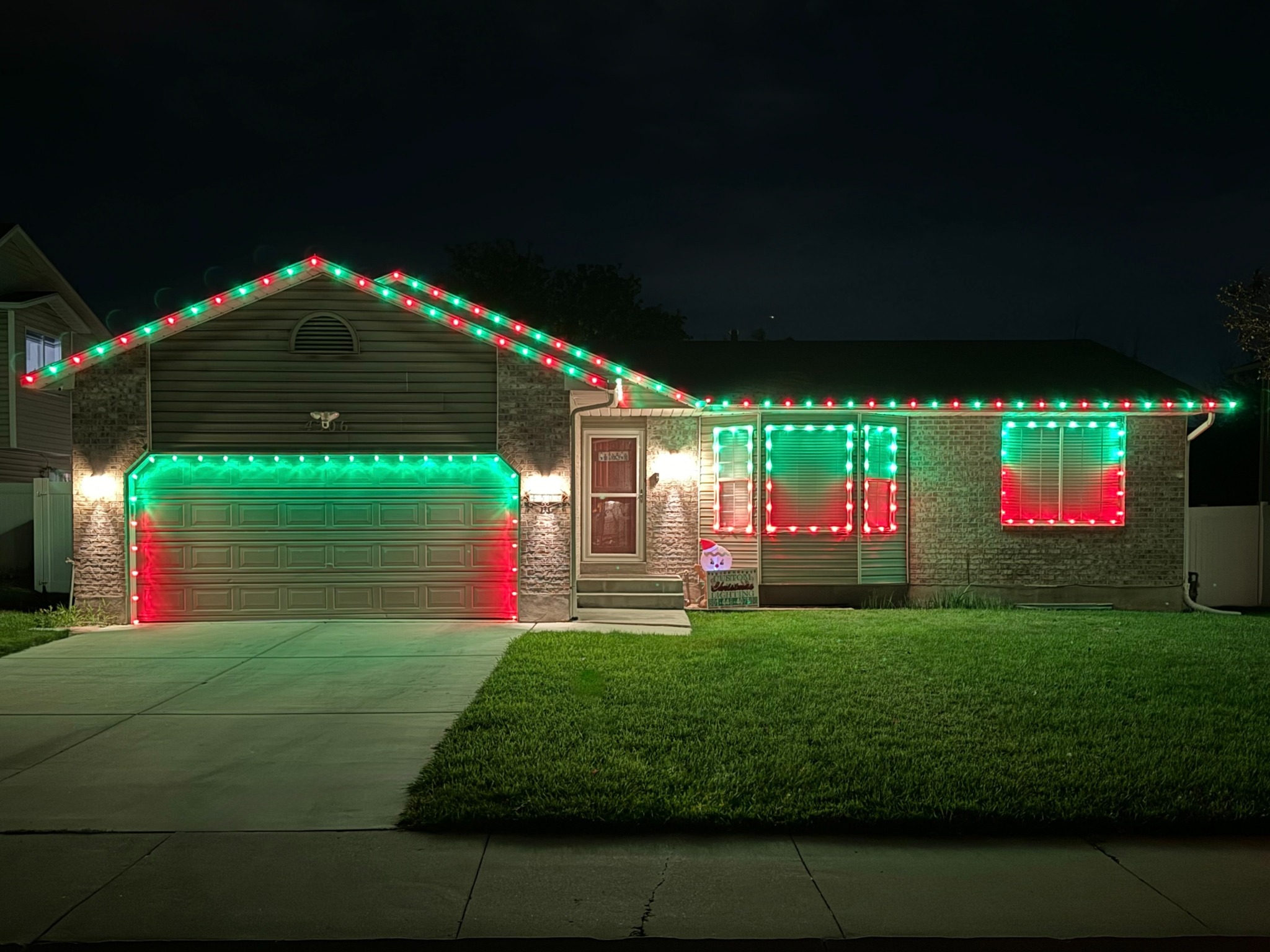Home with green and red lights along the roofline, windows, and garage